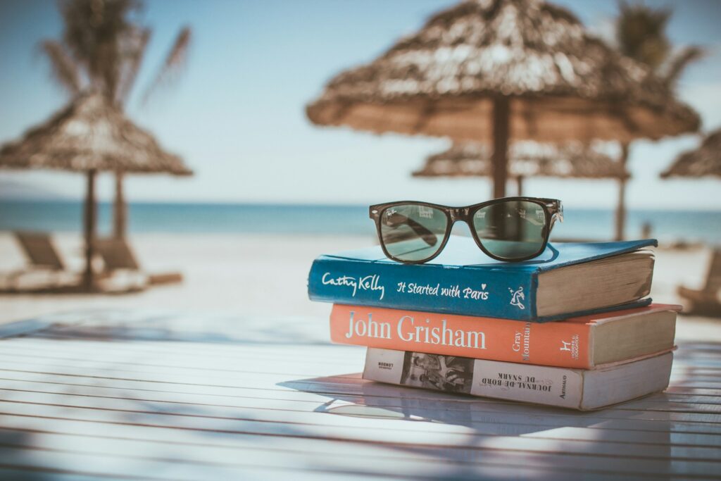 Self-care with paperback books and sunglasses on a beach