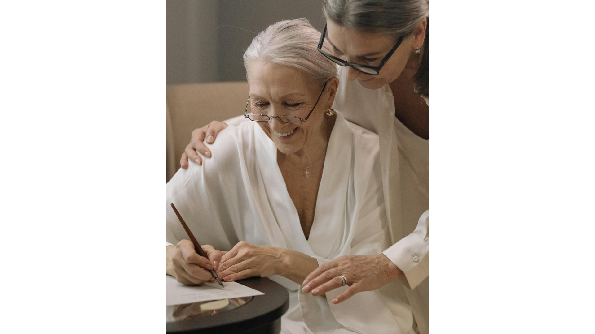 Taking care of elderly parents - aging mother with her daughter sitting at a table writing in a notebook