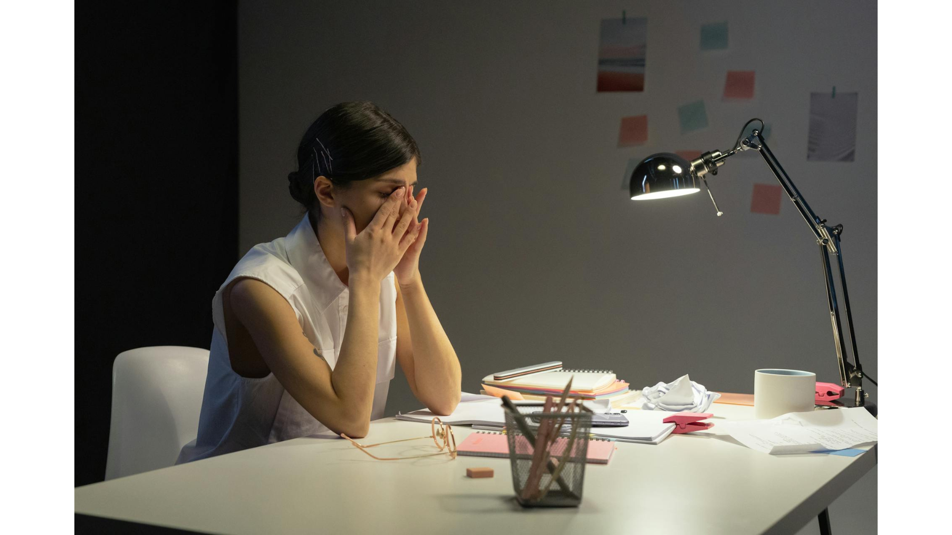 midlife woman covering her face with her hands while sitting at her desk at work - is it time for a midlife career change?